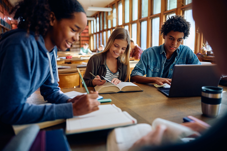 A group of students writing and smiling.