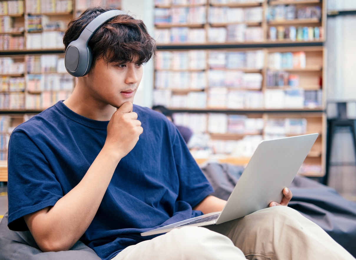 Male world language student with headphones and a laptop using ChatGPT as a conversation partner