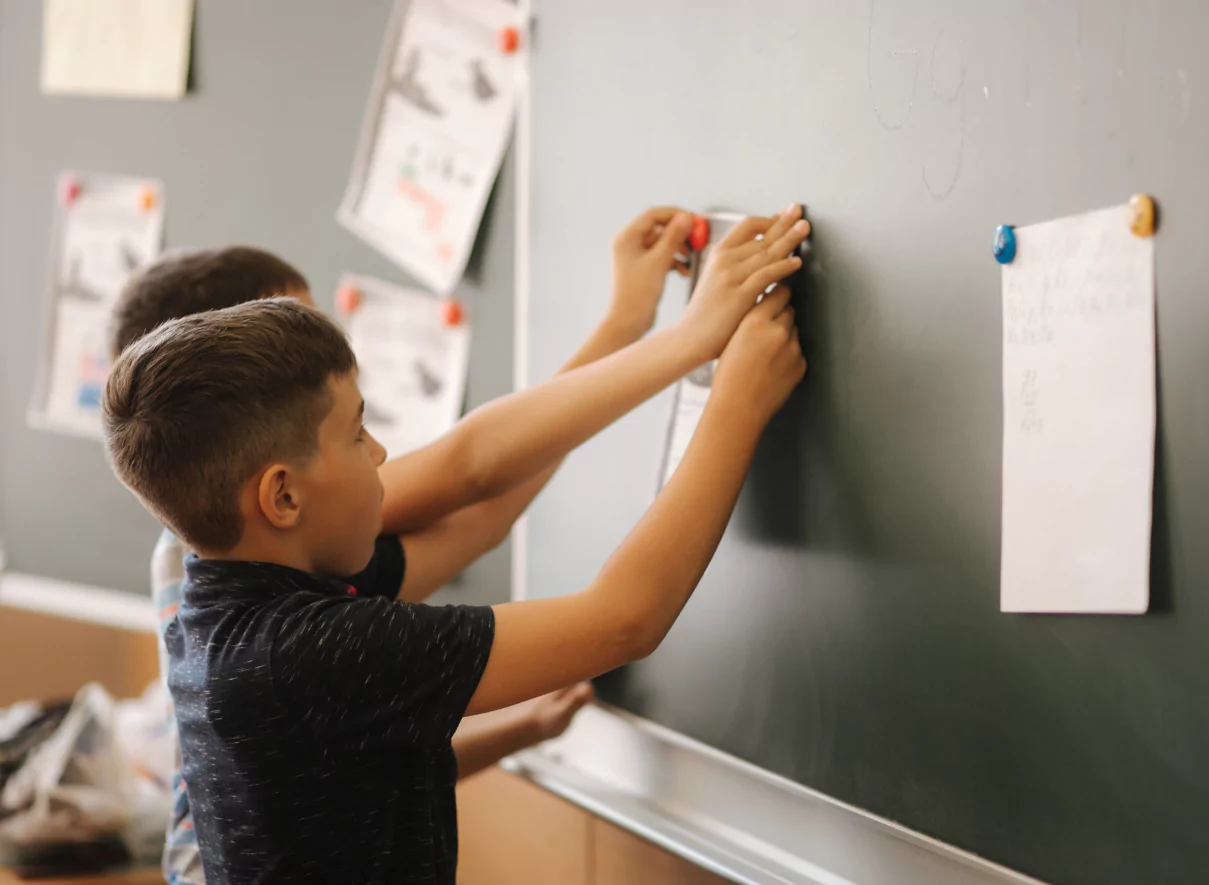 Two boys work together on math using vertical non permanent surfaces